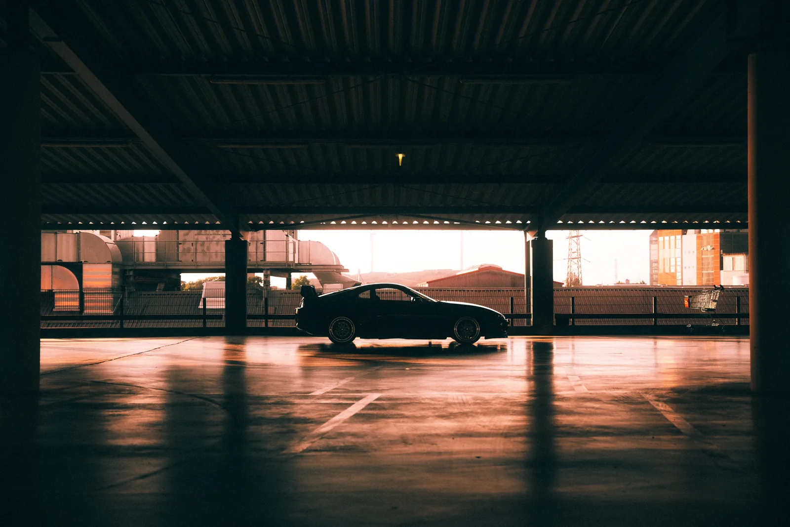 Dunkler Sportwagen in einem warm beleuchteten Parkdeck — Automobilfotografie Maurice Veith