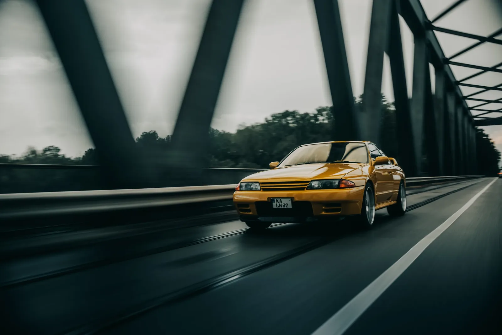 Nissan Skyline R32 in Fahrt zwischen den Streben einer Brücke — Automobilfotografie Maurice Veith