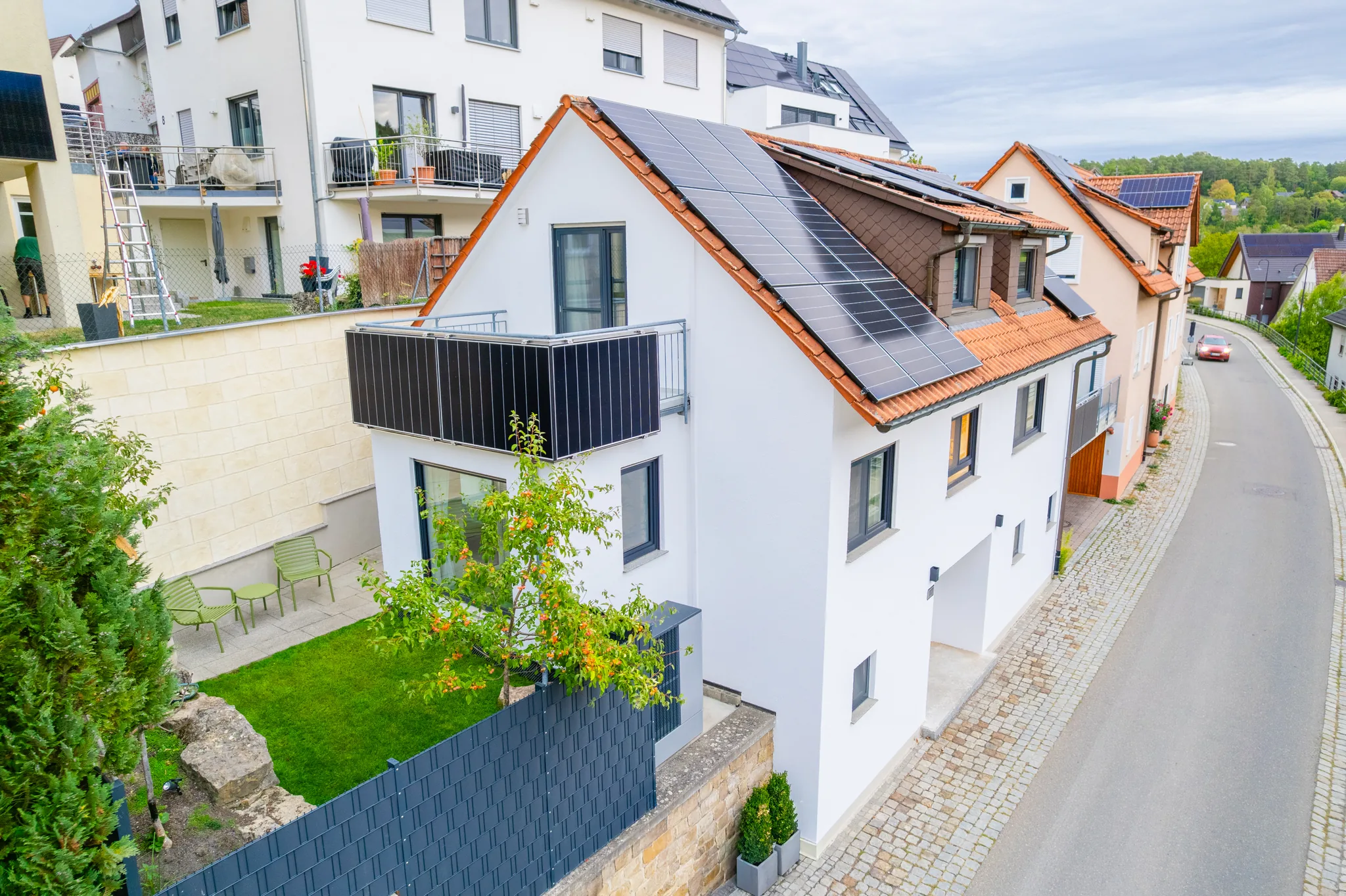 Luftbild: Haus am Hang mit Photovoltaikdach und Garten – Grafenau