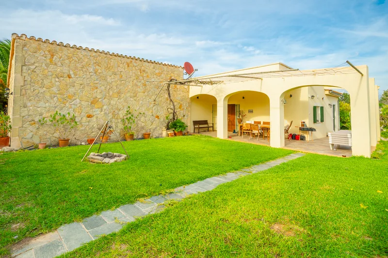 Gartenseite der Finca mit Natursteinwand und Bogenterrasse – Mallorca