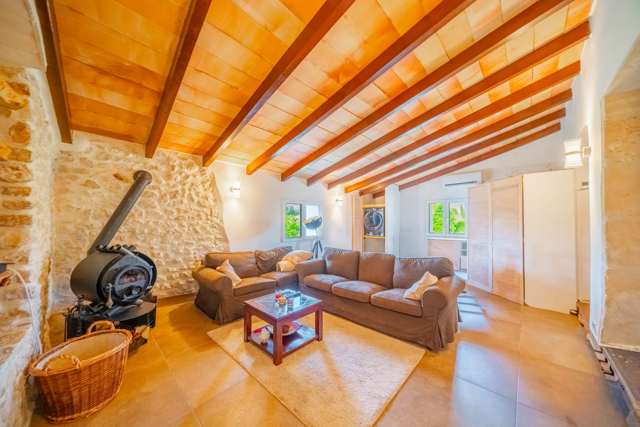 Wohnraum mit Natursteinwand, Holzbalkendecke und Kaminofen – Finca Mallorca