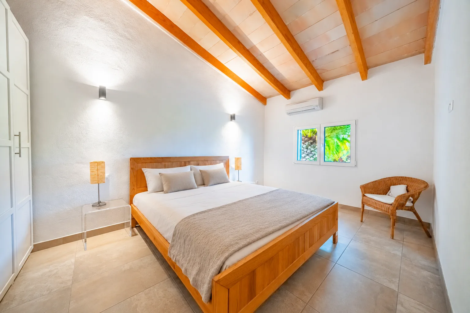 Schlafzimmer mit Holzbett und Korbsessel – Finca Mallorca