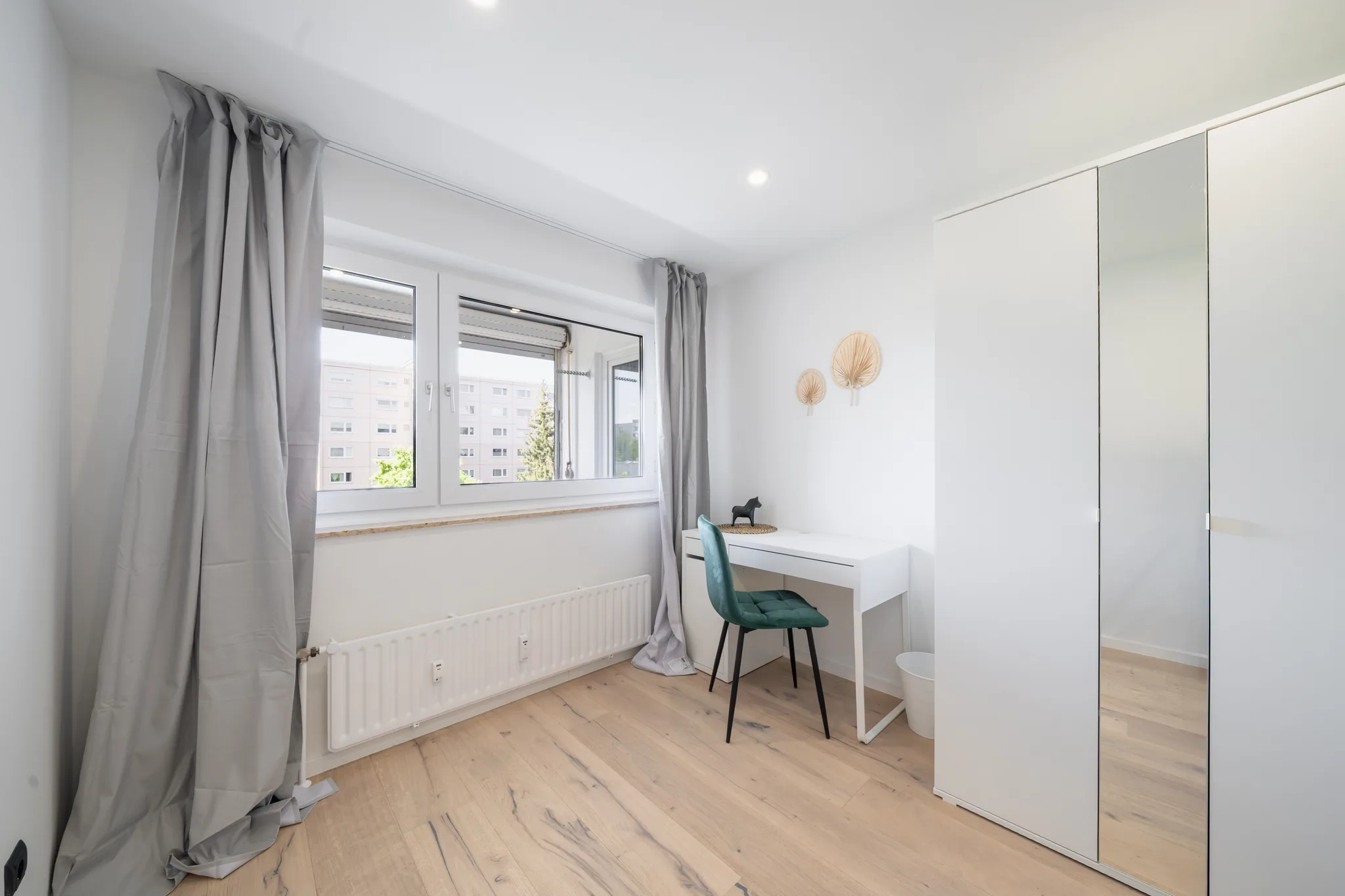 Zimmer mit Schreibtisch, grünem Stuhl und Fenster – München