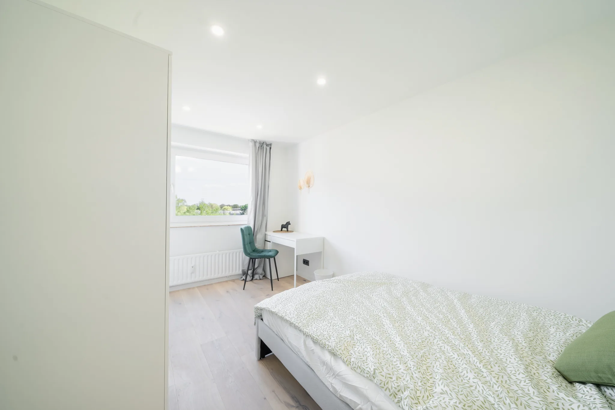 Zimmer mit Bett und grünem Kissen – München