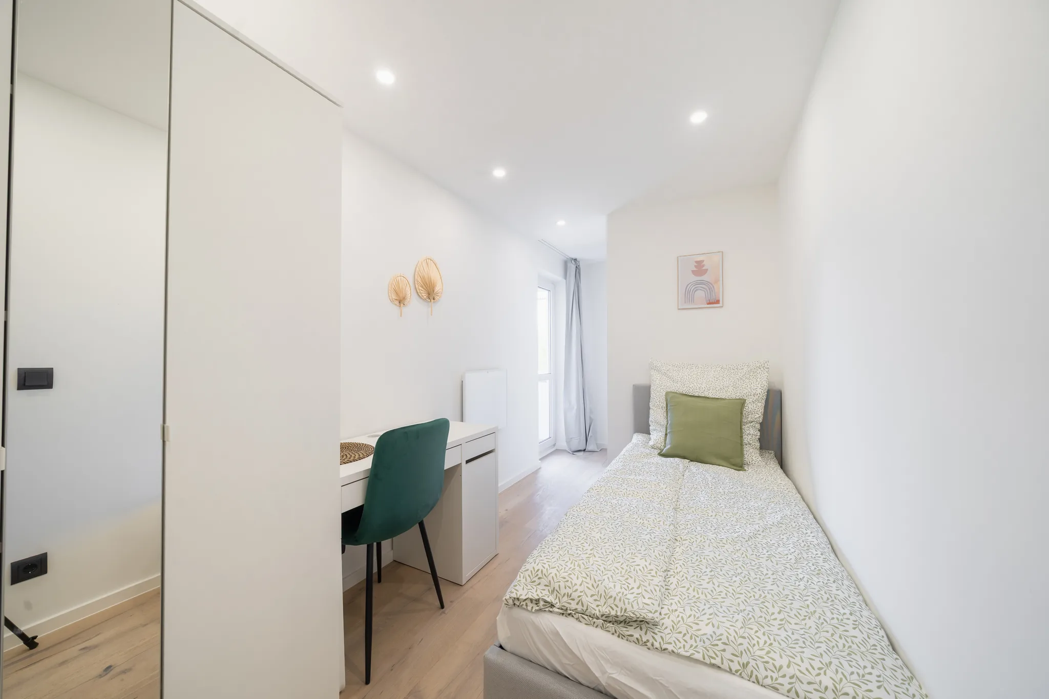 Schmales Zimmer mit Bett, Schreibtisch und Wandspiegel – München
