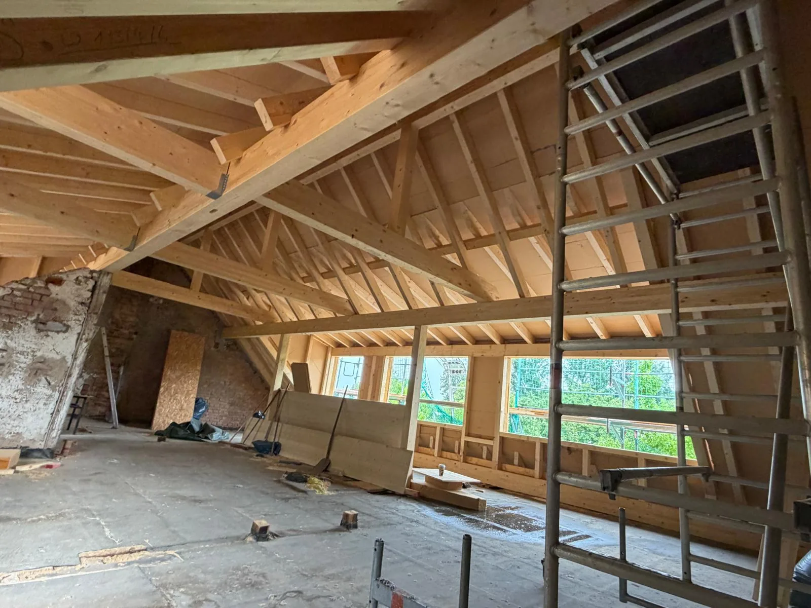 Ausgangsfoto: Dachgeschoss im Rohbau mit neuem Dachstuhl, Rollgerüst und Fensteröffnungen